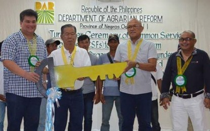 <p><strong>COMMON FACILITIES.</strong> Departrment of Agrarian Reform-6 Regional Director Stephen Leonidas (2<sup>nd</sup> from right) and Assistant Regional Director Antonio del Socorro (right)  turn over the symbolic key to the PHP23.5 million worth of common service facilities for five agrarian reform beneficiaries organizations to  Governor Alfredo Marañon Jr. (2<sup>nd</sup> from left)  and Silay City Mayor Mark  Golez in rites held at Bacolod Pavillon Hotel on Wednesday (April 11, 2018). (<em>Photo courtesy of DAR-Negros Occidental I</em>) </p>